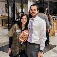 Two alumni pose holding a football at the Fowling Fun Event